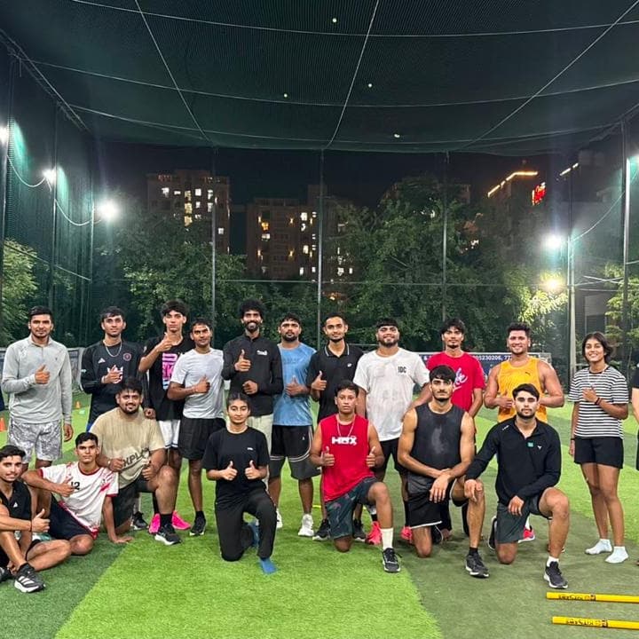 Group of athletes posing together after an evening sports training session on an outdoor turf field in Jaipur