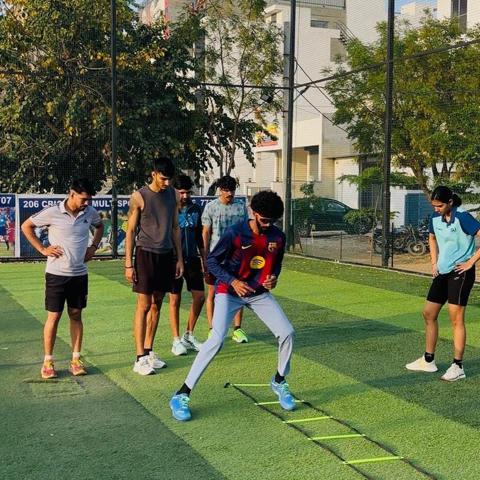 ACL PhysioHab physiotherapist demonstrating agility-ladder footwork to a group of athletes on an outdoor turf field
