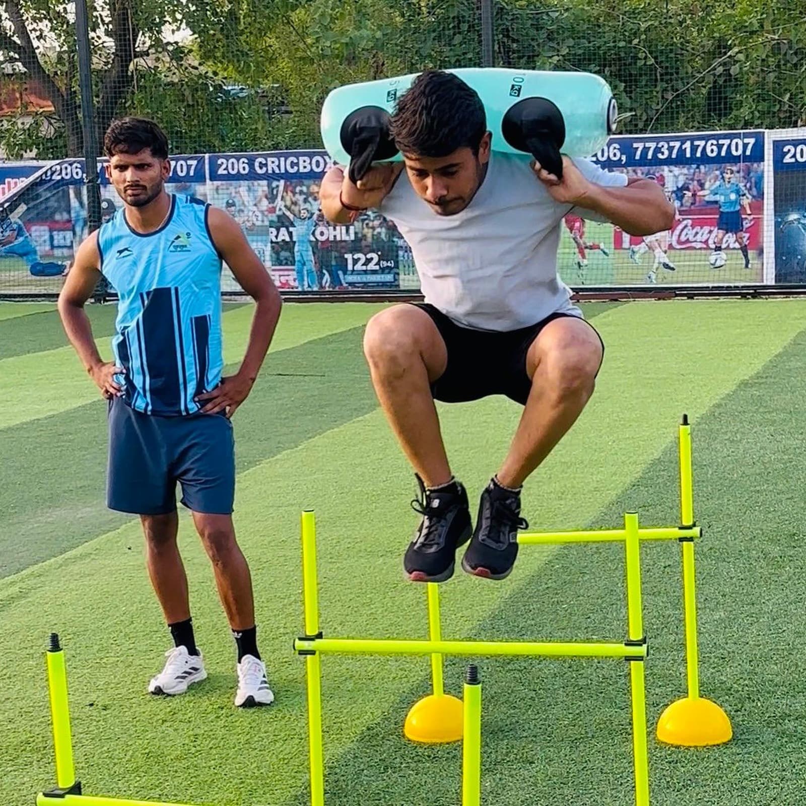 Athlete performing a weighted double-leg hurdle jump as part of return-to-sport plyometric testing, coach observing