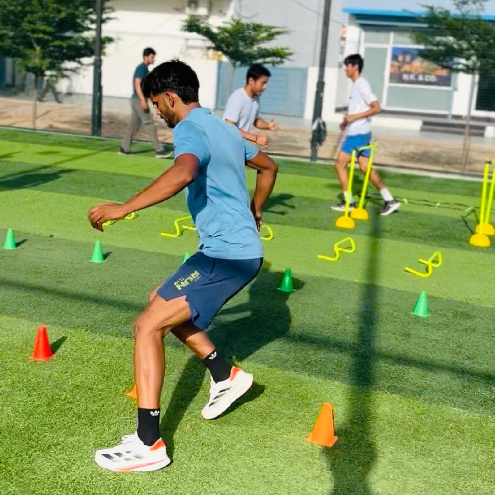 Athletes performing lateral cone-drill footwork during an outdoor agility and speed session